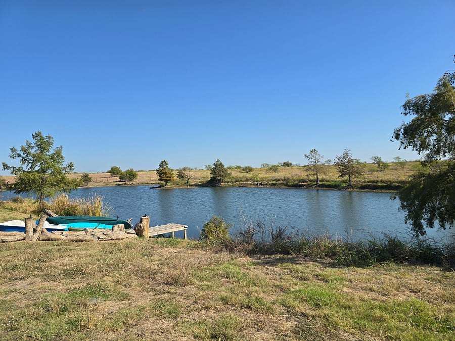 A pedal boat and a canoe pulled up beside a little dock on the far side of the lake, under a clear blue sky.