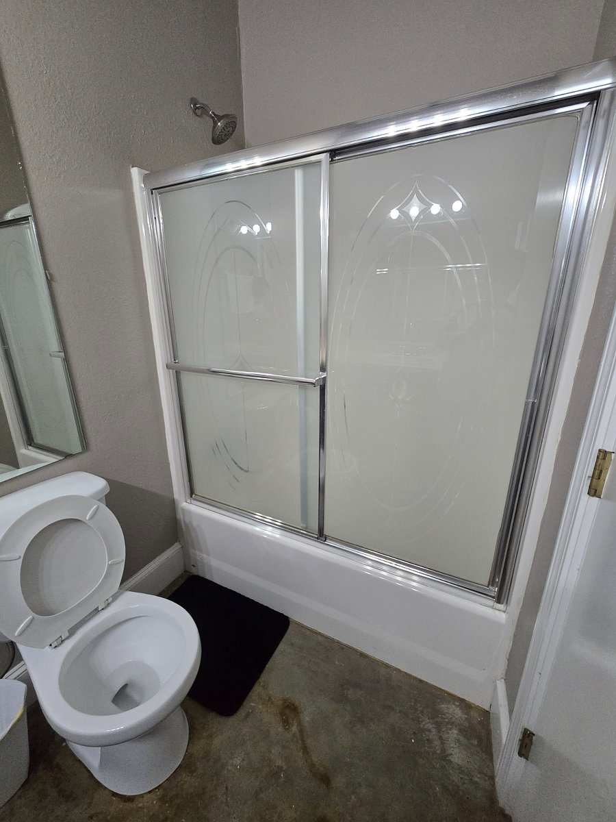 Studio 201 bathroom: a tub with frosted sliding shower doors, and the toilet.