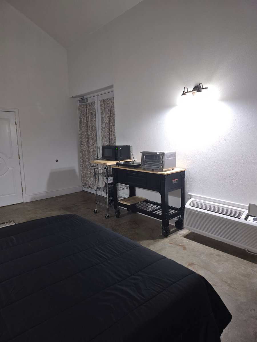 Studio 201: the foot of the bed facing the kitchenette carts, curtained double doors and the wall A/C unit.