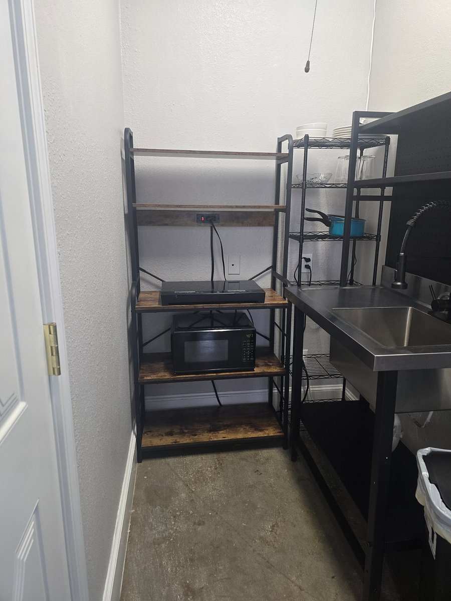 Studio 203 kitchenette: open shelving with a microwave and hot plate, beside a stainless steel sink.